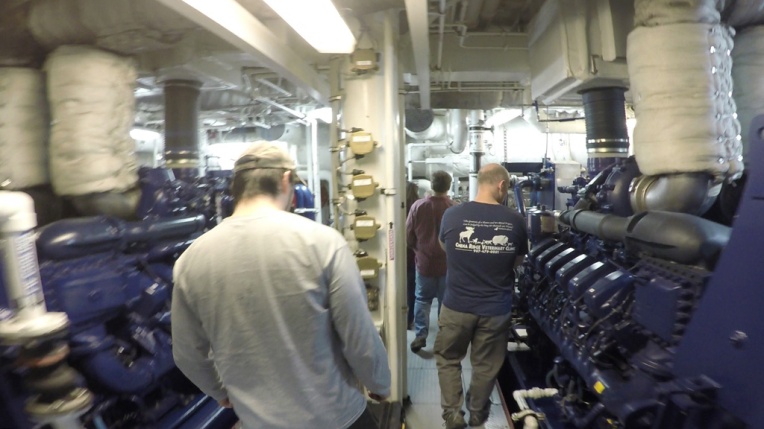 Brandon Hassett and Rob Rember walk between two of Sikuliaq’s four diesel engines.